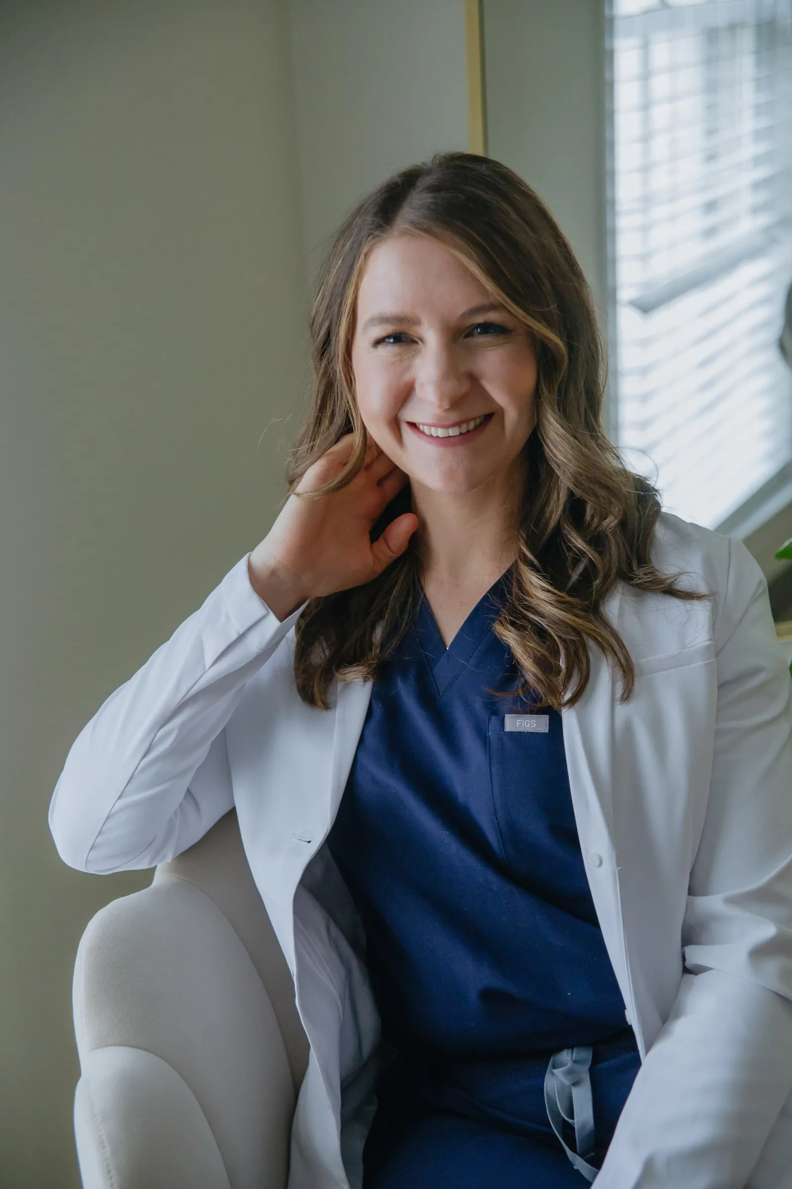 Danielle Wise, NP, in a white coat by a window