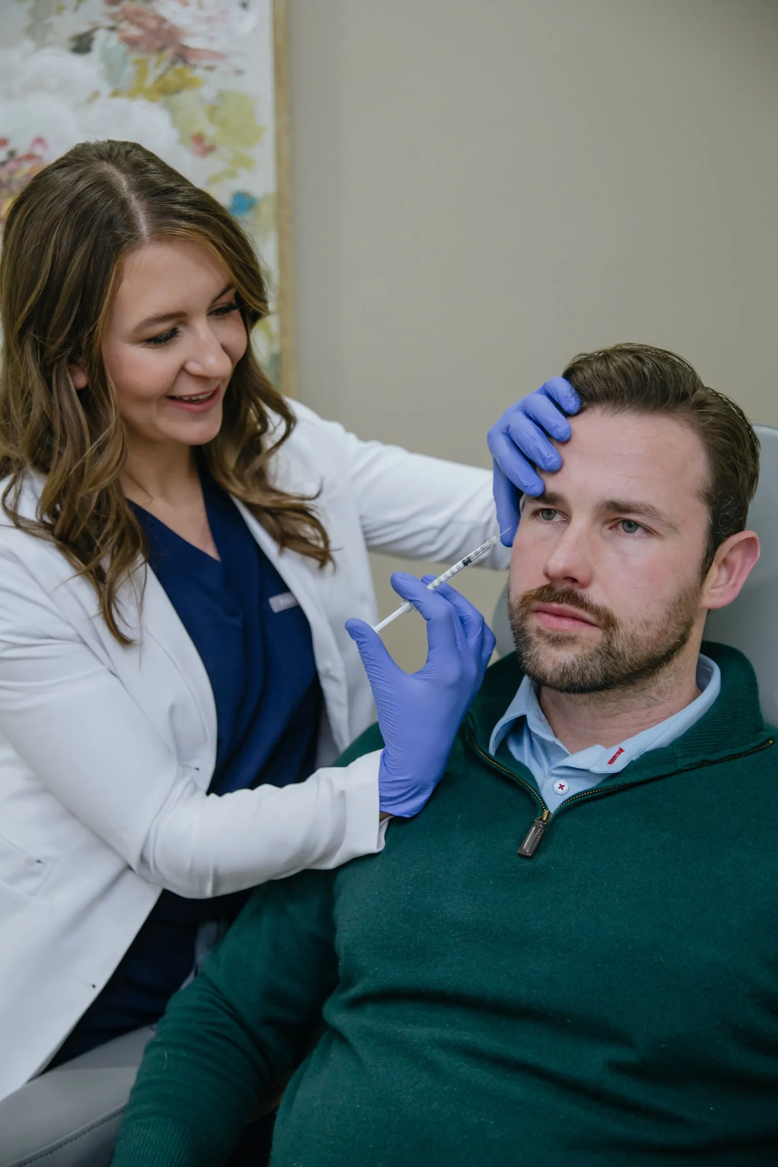 Danielle Wise, NP, administering a forehead injection to a seated male patient